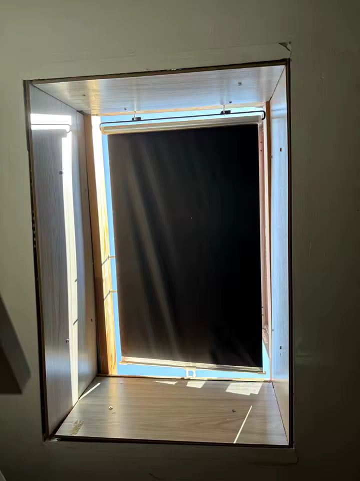 Store occultant installé sur une fenêtre de toit type Velux pour assombrir une pièce sous combles